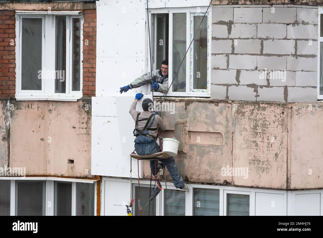 Tiraspol, Moldova - 10 dicembre 2022: Costruttore di alta quota isola la facciata di un edificio di appartamenti con plastica espansa. Casa isolante aerata Foto Stock