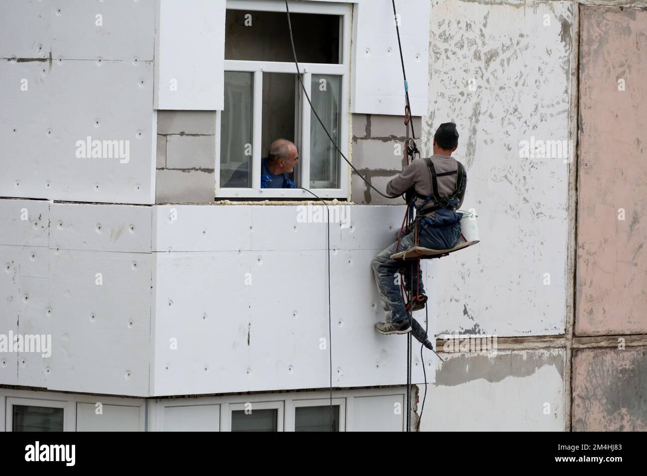 Tiraspol, Moldova - 10 dicembre 2022: Costruttore di alta quota isola la facciata di un edificio di appartamenti con plastica espansa. Casa isolante aerata Foto Stock