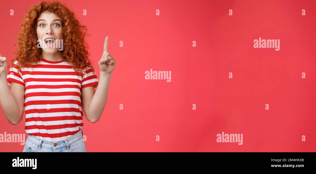 OMG affascinante negozio controllare. Impressionato eccitato buon-osservare redhead arricciamente emotivo ragazza goccia mascella stupito felice che punta sulle dita dell'indice Foto Stock