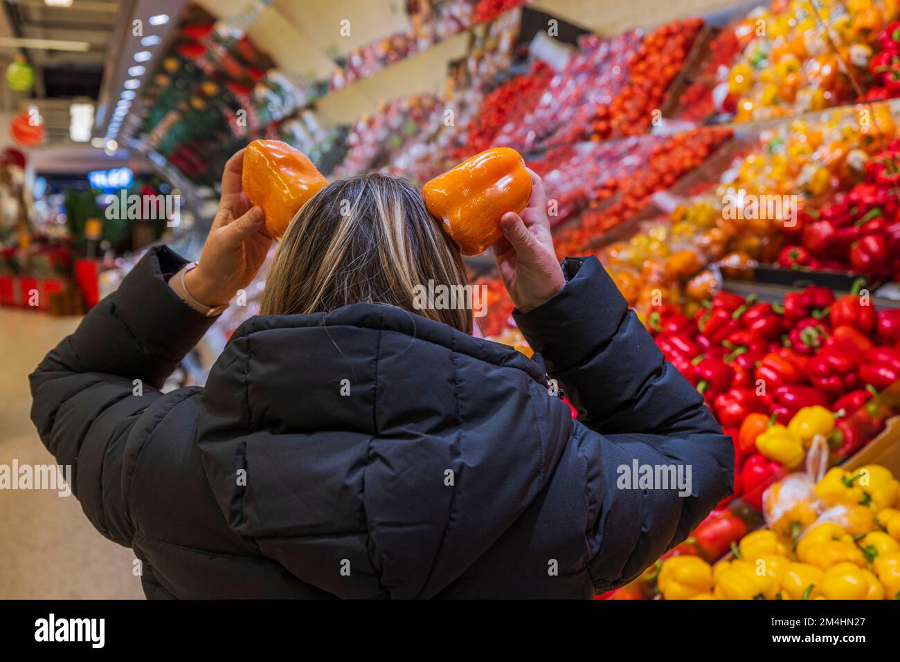 Vista ravvicinata di una donna che imbrogliava con la paprika arancione nel reparto del supermercato delle verdure. Foto Stock