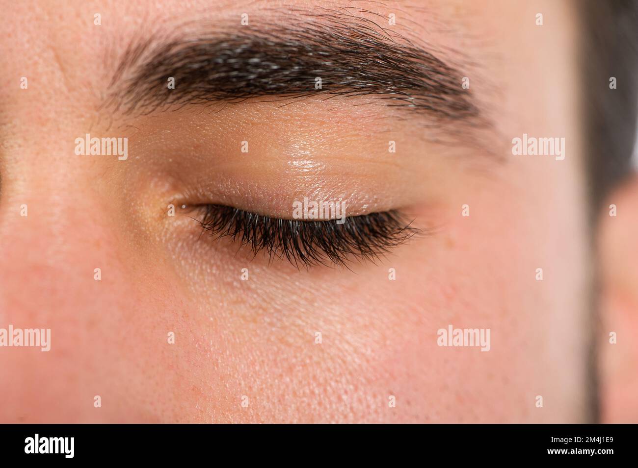 Trattamento di allungamento e infolving delle ciglia maschili, macro dettagli dell'occhio chiuso di un uomo Foto Stock