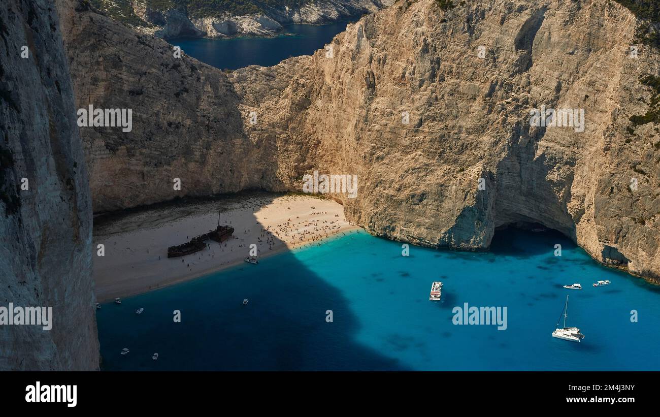 Paralia Navagio, Shipwreck Beach, scogliera rocciosa, naufragio MV Panagiotis, molti turisti sulla spiaggia, barche da escursione, blu e turchese cristallo chiaro Foto Stock