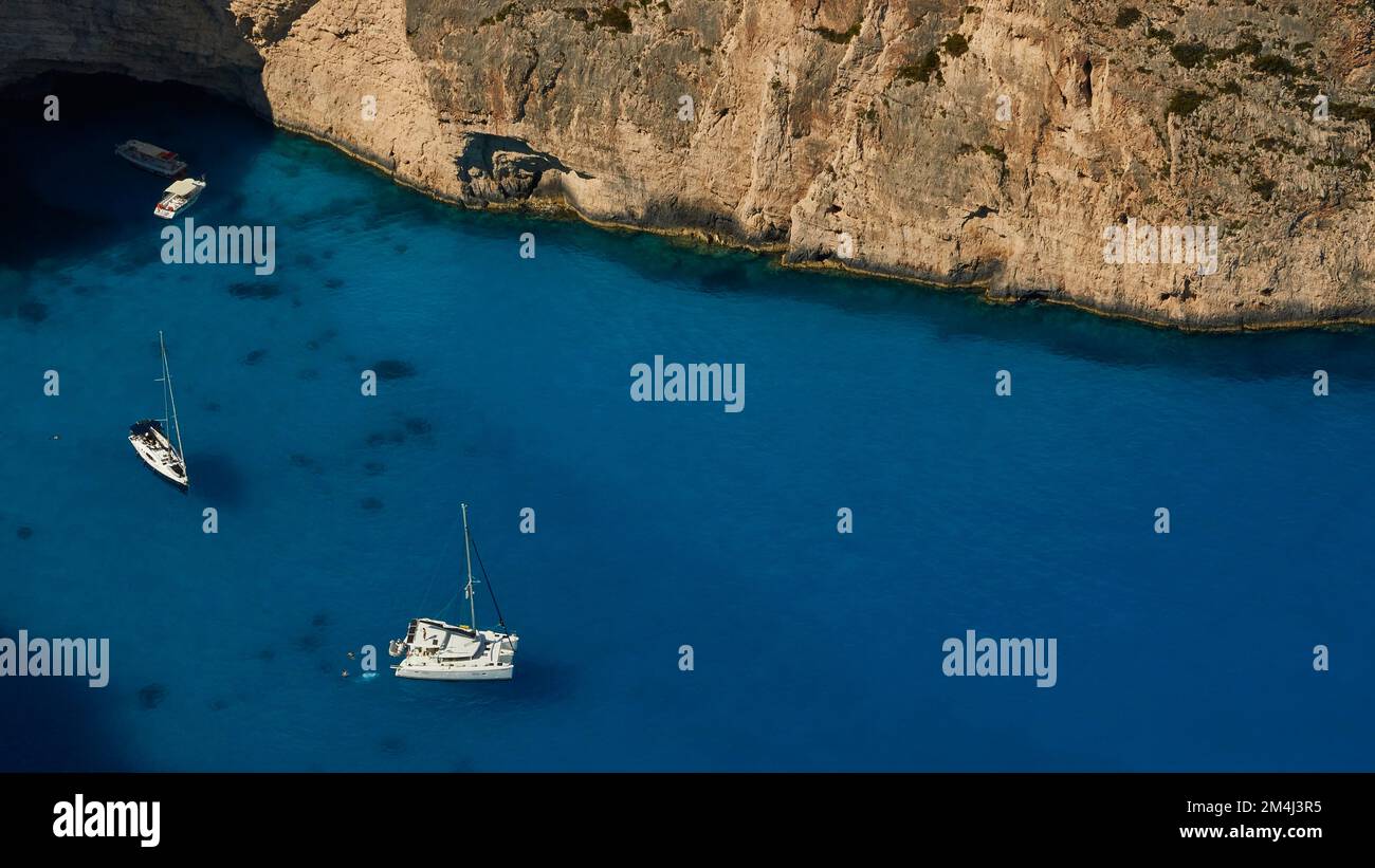 Paralia Navagio, Shipwreck Beach, scogliera rocciosa, naufragio MV Panagiotis, barche da escursione, barca a vela, catamarano, mare cristallino blu e turchese Foto Stock