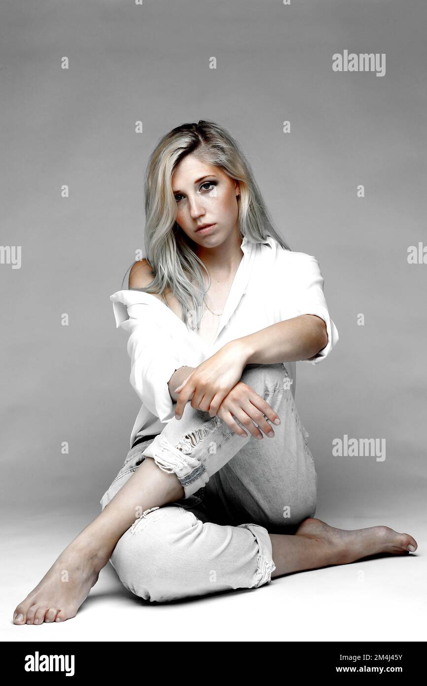 Giovane donna bionda seduta Foto Stock