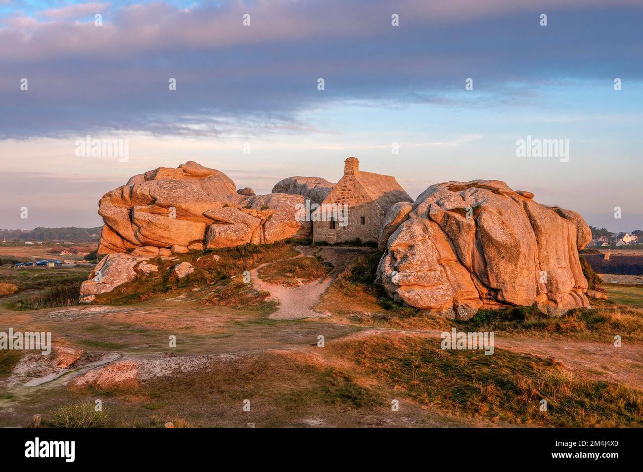 La Casa della Guardia (Corps de Garde) ('Casa doganale') tra due enormi rocce di granito, Site de Meneham, Meneham, Kerlouan, Dipartimento Finistere Foto Stock