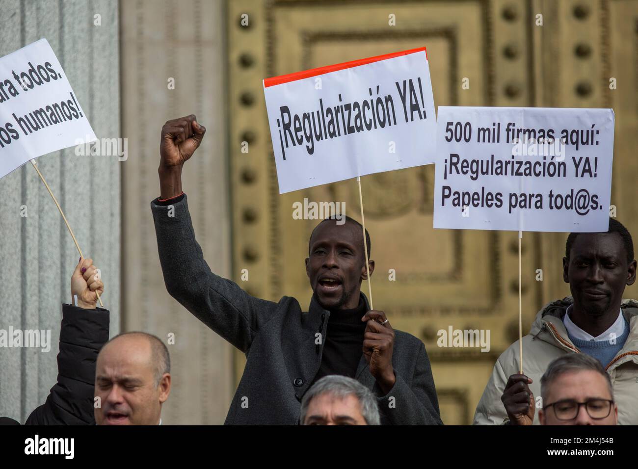 Madrid, Spagna. 21st Dec, 2022. Serigne Mbayé (centro), deputato regionale per United We Can all'Assemblea di Madrid, Gesti tenendo un cartello che dice “Regularization Now” durante un atto simbolico per consegnare più di 700.000 firme per la regolarizzazione dei migranti al Congresso spagnolo per celebrare il successo dell’iniziativa legislativa popolare per la regolarizzazione straordinaria dei migranti in Spagna. Credit: SOPA Images Limited/Alamy Live News Foto Stock