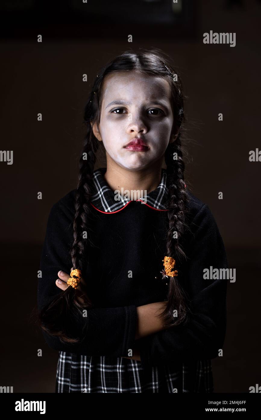 Ritratto di bambina con costume di mercoledì Addams durante Halloween.  Espressione seria e atmosfera scura con sfondo scuro Foto stock - Alamy