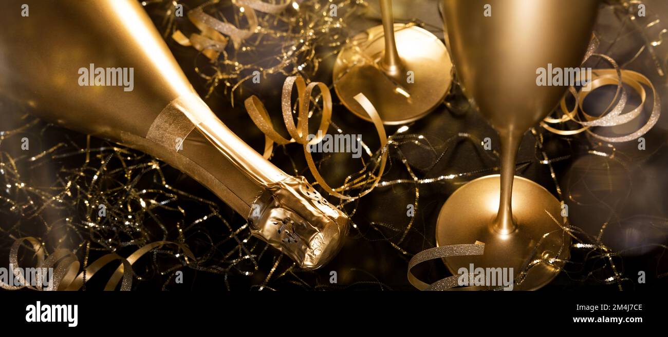 capodanno. bottiglia di champagne di lusso in oro con bicchieri e nastri dorati su sfondo nero. banner Foto Stock