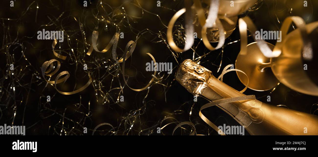 capodanno. bottiglia di champagne di lusso in oro con bicchieri e nastri dorati su sfondo nero. banner con spazio di copia Foto Stock