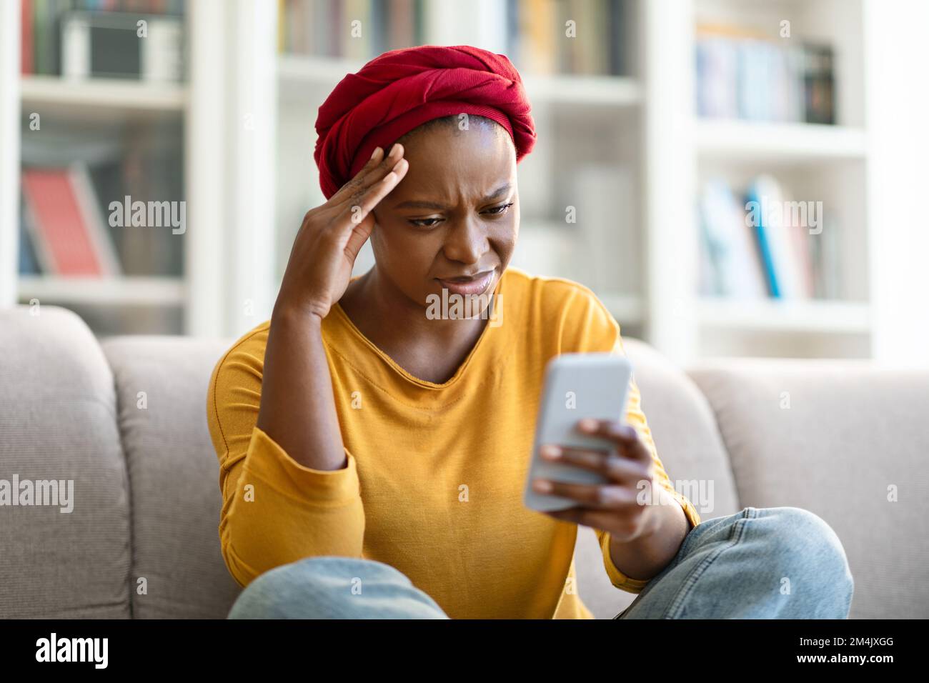 Donna ameriana africana ansiosa di leggere il messaggio al telefono Foto Stock