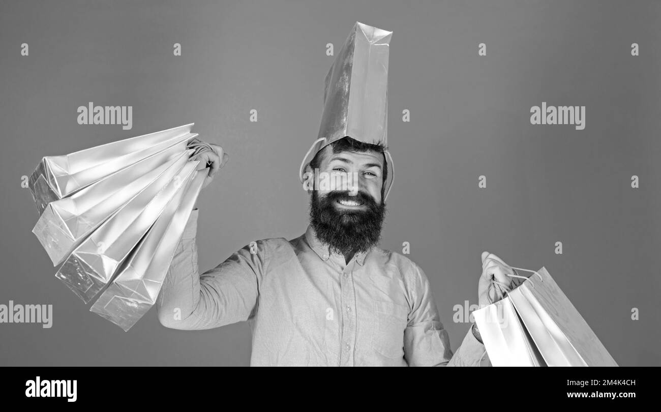 Uomo con barba alla moda e viso sorridente isolato su sfondo blu. Hipster in camicia rosa facendo shopping, grande spender. Felice uomo portatore Foto Stock