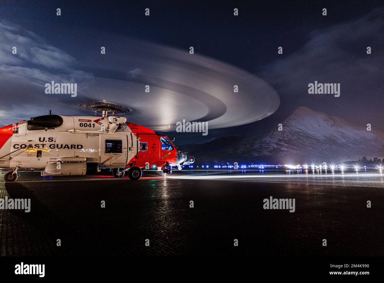 Una stazione aerea Kodiak MH-60 Jayhawk elicottero conduce operazioni di atterraggio notturno all'aeroporto statale di Kodiak Benny Benson il 22 marzo 2022. Barometer Mountain può essere visto sullo sfondo. STATI UNITI Guardia costiera foto di Scott Kellerman. Foto Stock