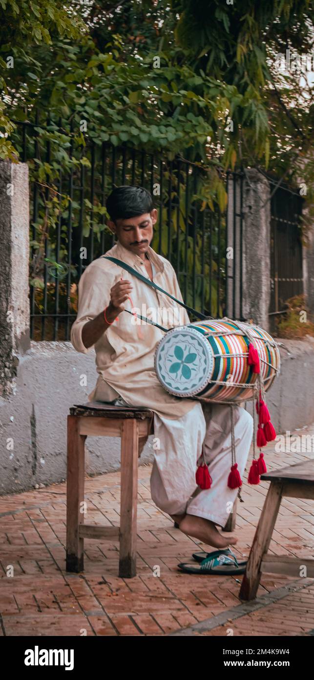 Un uomo seduto e suonando il tamburo pacificamente per le strade di Karachi Foto Stock