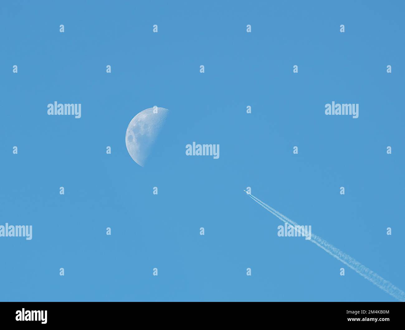 Aereo non identificato che viaggia in direzione della luna su un cielo blu. messa a fuoco selettiva, Foto Stock