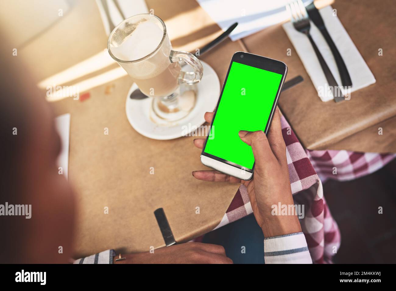 Chi potrebbe chiamarmi ora. Sopra la spalla di una persona non riconoscibile che naviga sul telefono mentre è seduto a un tavolo. Foto Stock