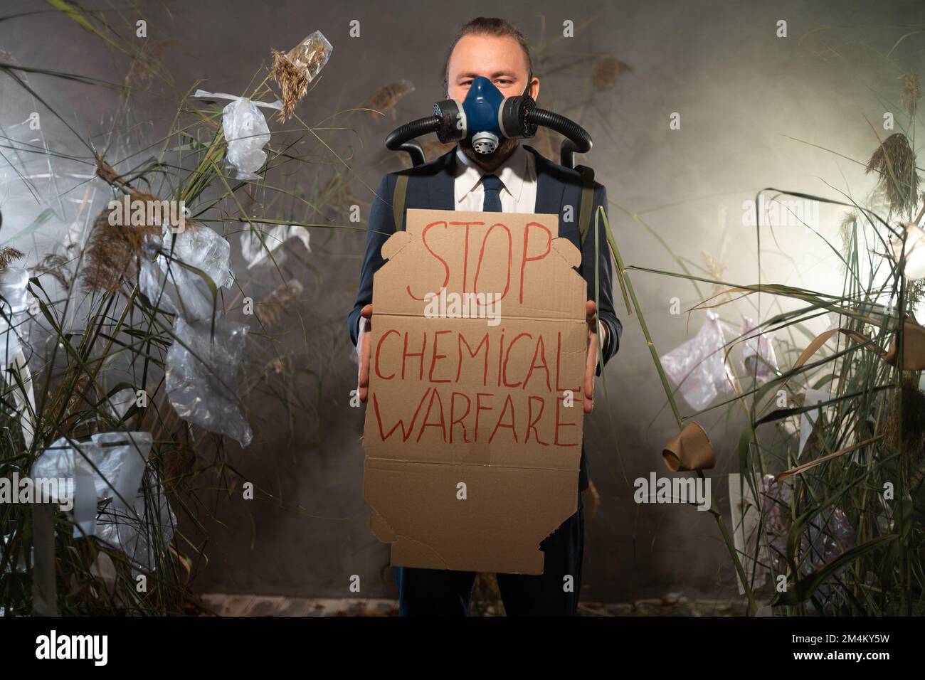 Giovane uomo d'affari in maschera a gas con poster Stop guerra chimica. Spazio di copia Foto Stock