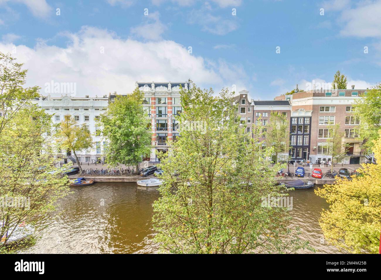 alcuni alberi e barche in acqua in una giornata di sole con cielo blu, nuvole bianche e foglie gialle Foto Stock