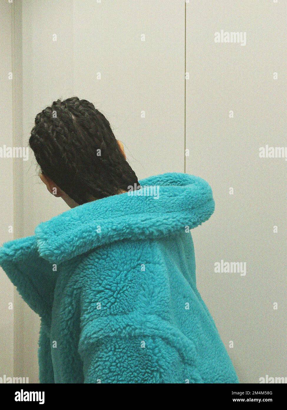 Schiena donna con capelli dreadlocks e cappotto blu Foto Stock