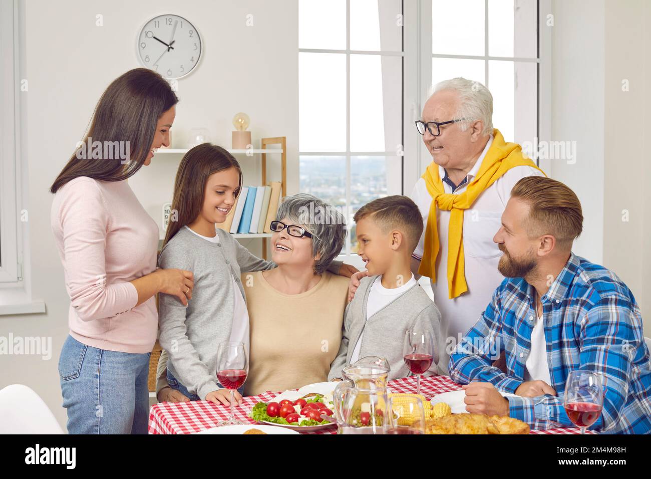 Felice nonna abbracciando i suoi nipoti piccoli ad una cena di famiglia accogliente a casa Foto Stock