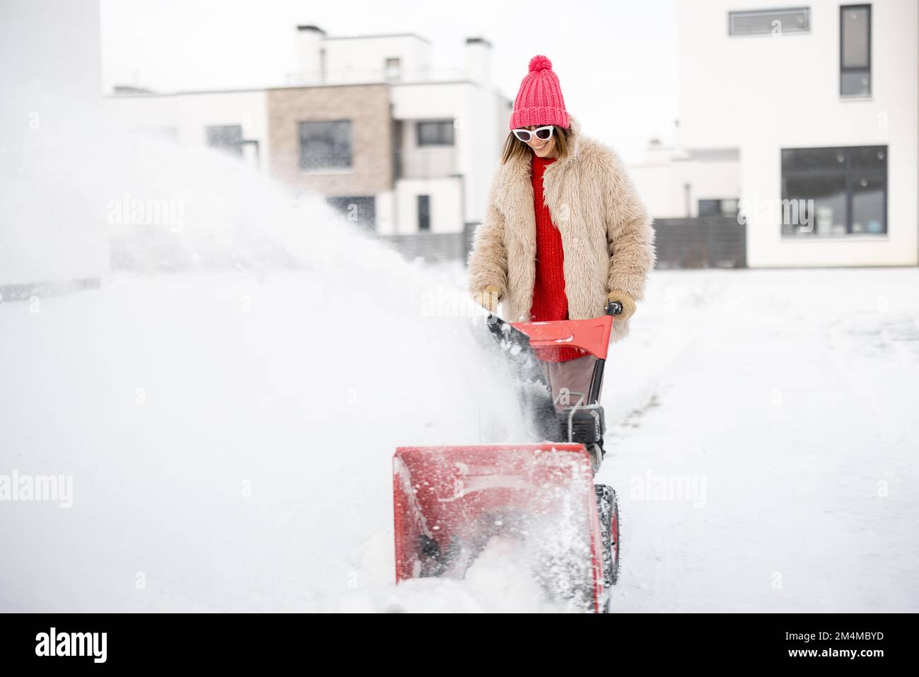 Donna rimuove la neve con un lancianeve vicino casa Foto Stock
