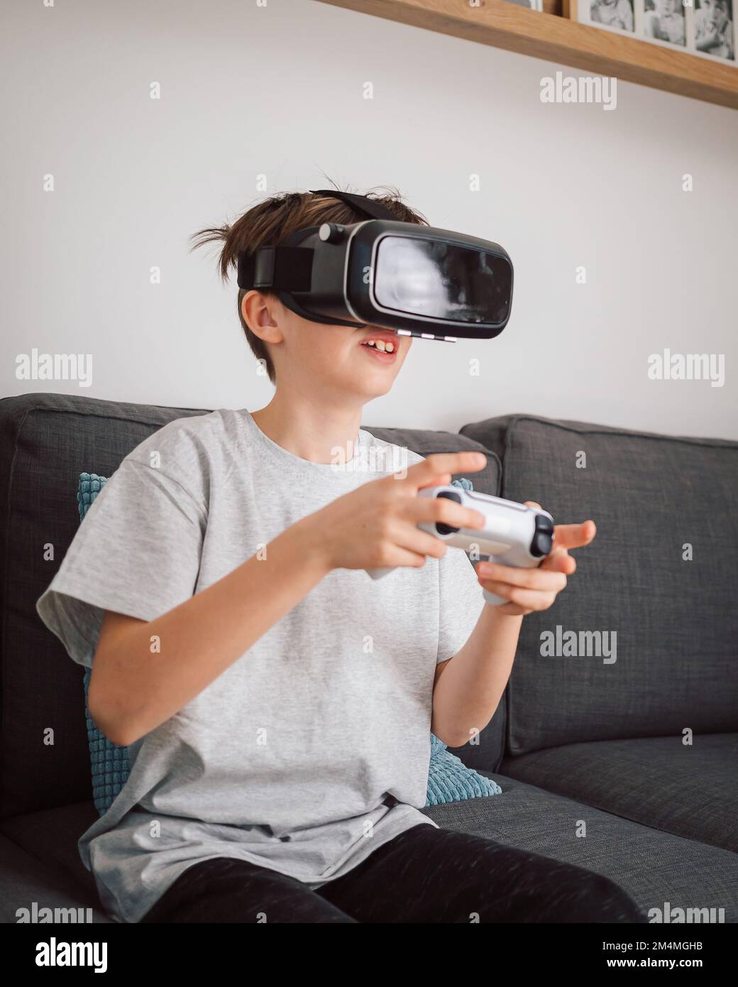 Ragazzo che si diverte a giocare a giochi di simulazione, utilizzando cuffie e controller per la realtà virtuale. Concetto di bambini e tecnologia moderna. Foto Stock