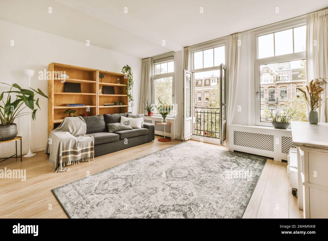 un soggiorno con pavimento in legno e grandi finestre che si affacciano sul cityscapeatrooms com Foto Stock