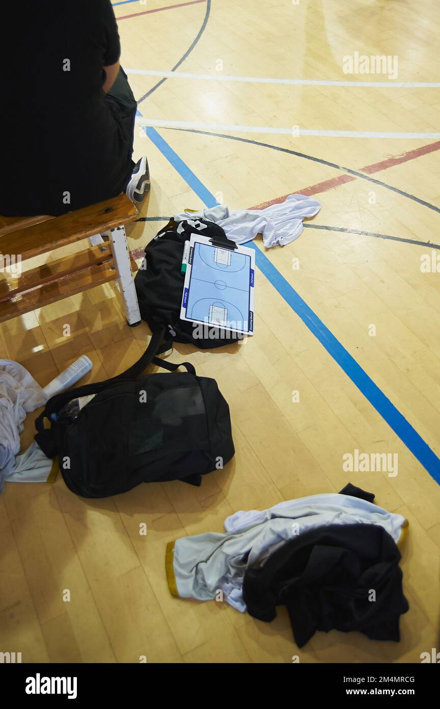 Ardesia per dare istruzioni di basket accanto al pullman sul pavimento e circondato da vestiti dei giocatori. Pianificare una partita di basket Foto Stock
