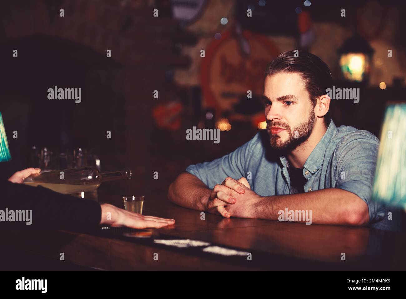 L'uomo con la barba siede al bancone del bar sullo sfondo del pub. Foto Stock