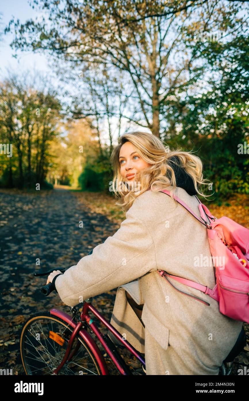Giovane donna caucasica attraente cavalcare in bicicletta nel parco il giorno caldo in autunno. Foto Stock