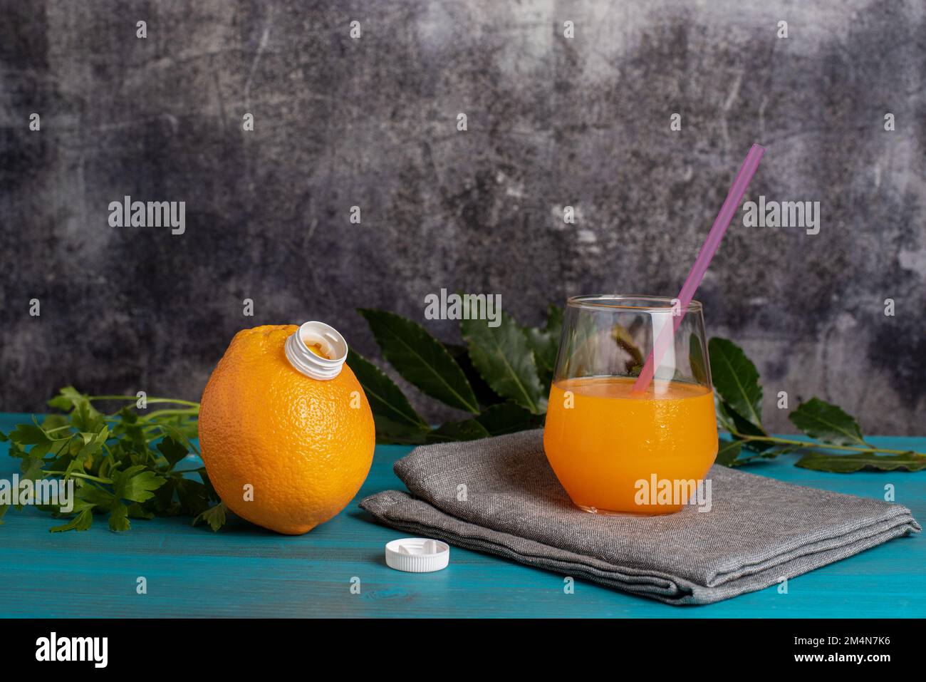 Bicchiere di succo d'arancia accanto a un'arancia con un beccuccio aperto, da cui proviene il succo. Foto Stock