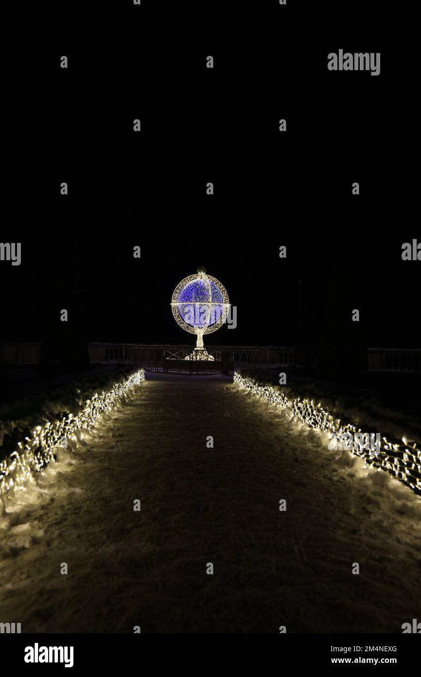 Percorso verso l'arte della luce nel Giardino reale di luce del Palazzo a Wilanów in Polonia, in una serata invernale buia, raffigurante una sfera armillare Foto Stock