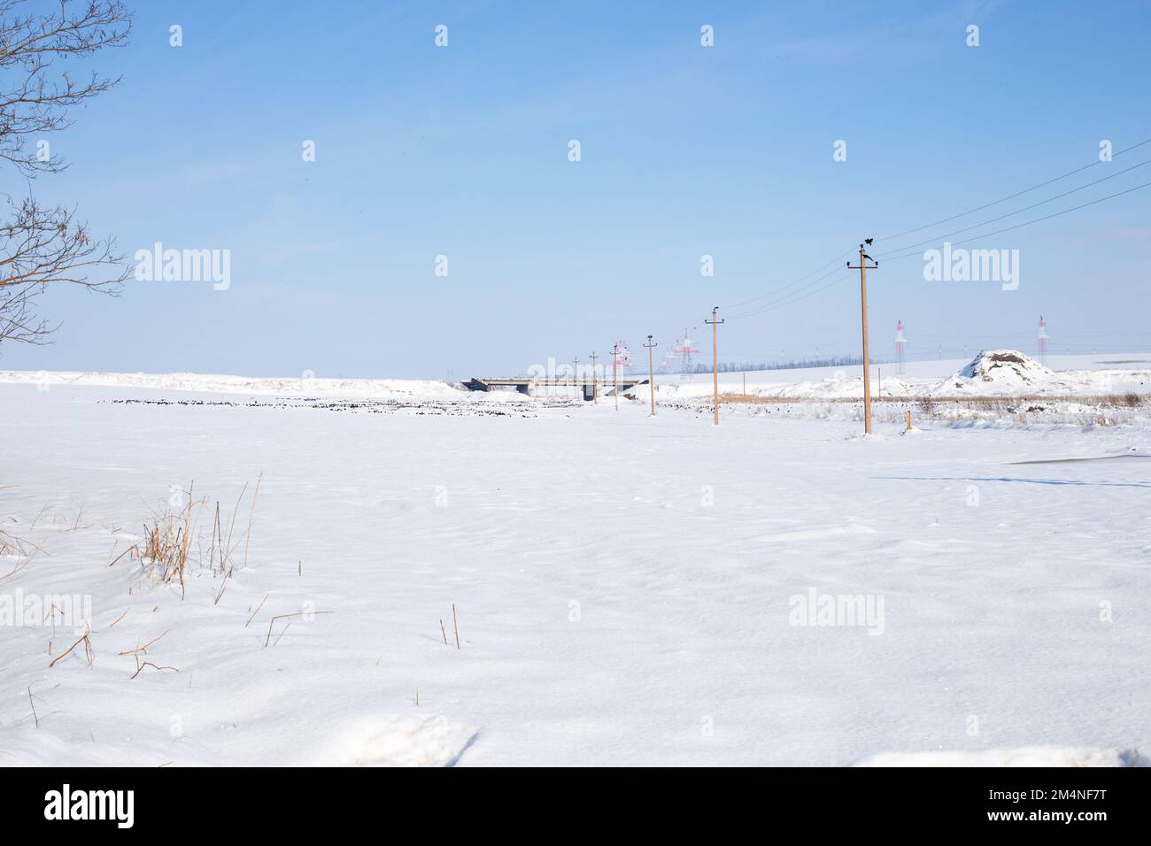 Un campo coperto di neve bianca e un ponte in costruzione sullo sfondo. Foto Stock