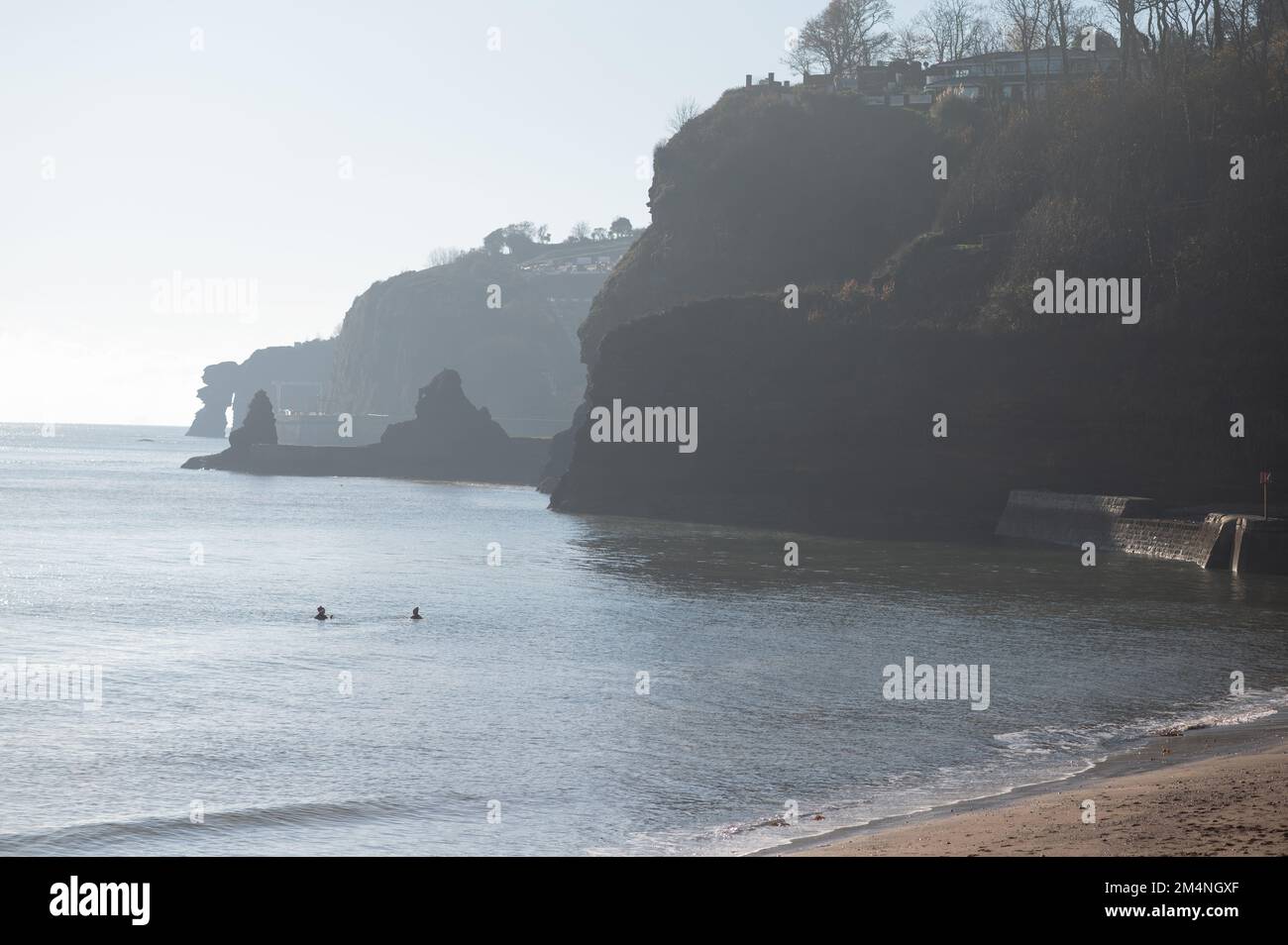 Due persone nel freddo mare d'inverno con silhouette bassa Foto Stock