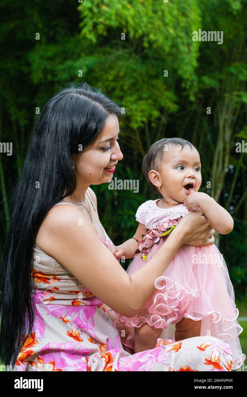 madre latina che guarda la sua piccola brunetta, che è molto felice con una mano sulla bocca Foto Stock