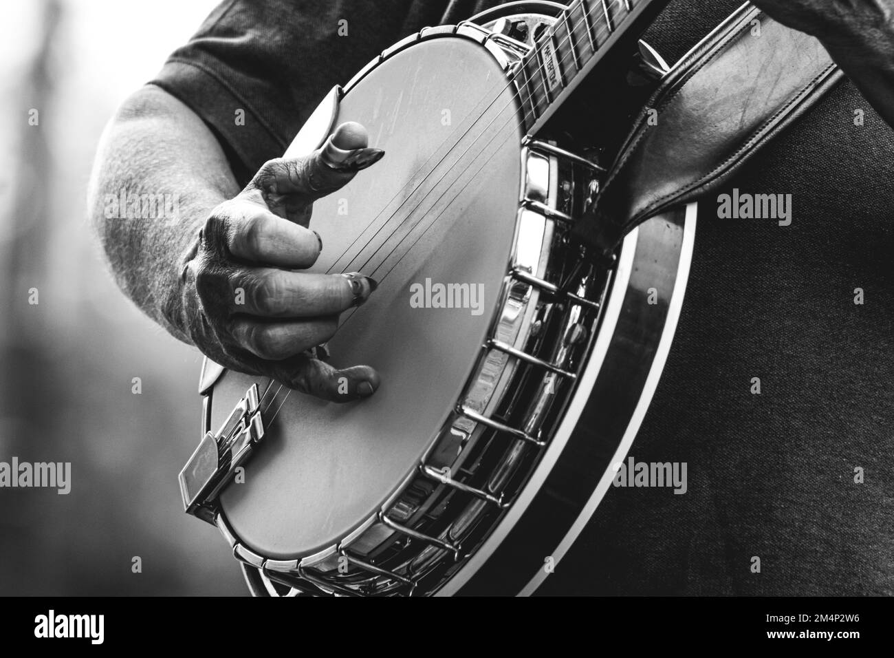 Primo piano di un uomo maturo che suona banjo a cinque corde, strumento musicale, all'esterno in bianco e nero, primo piano di musica bluegrass a mani e dita Foto Stock