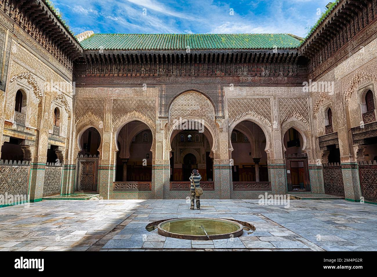 Cortile interno con bacino d'acqua, visitatori fotografando facciate in legno e portici, ornamenti, 14th ° secolo college islamico, Medersa Bou Inania, Fes Foto Stock