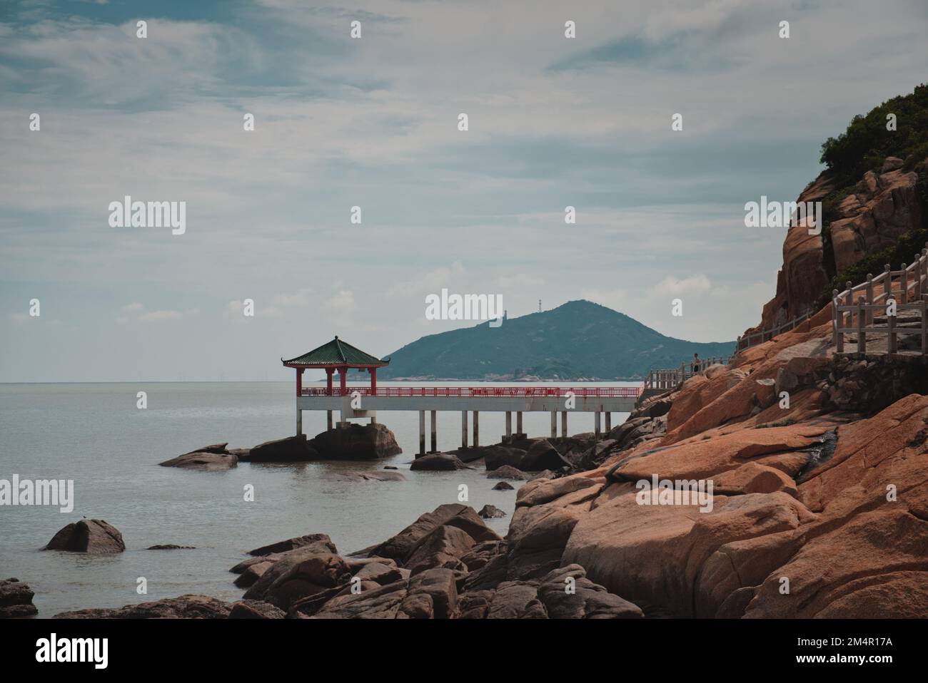 il drago artiglio roccia e massi vicino a un molo in mare Foto Stock