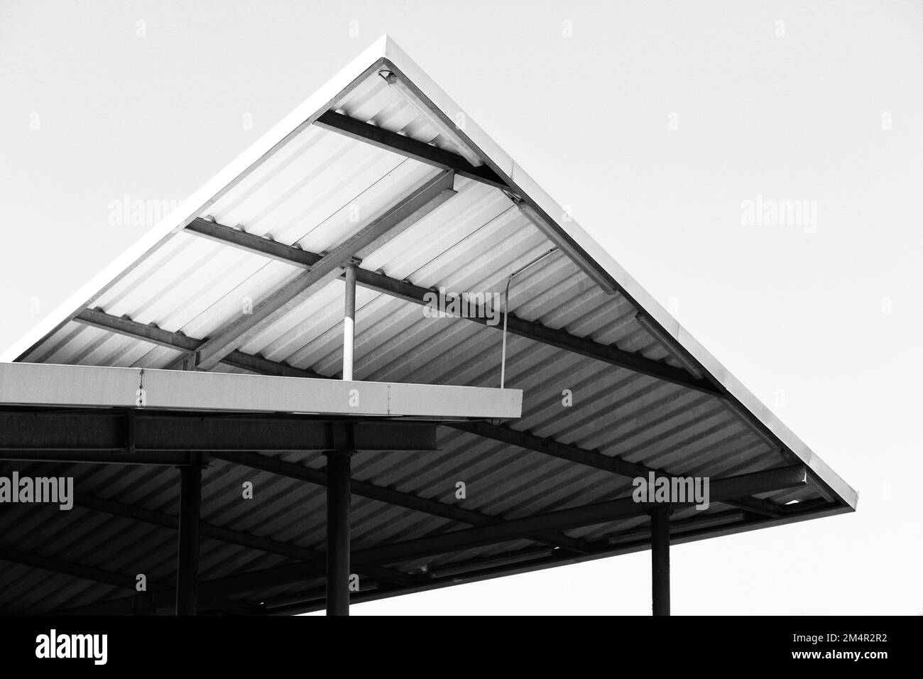 L'angolo di una vecchia costruzione di tetto in metallo bianco e nero si innalza nel cielo e forma elementi grafici. Foto Stock