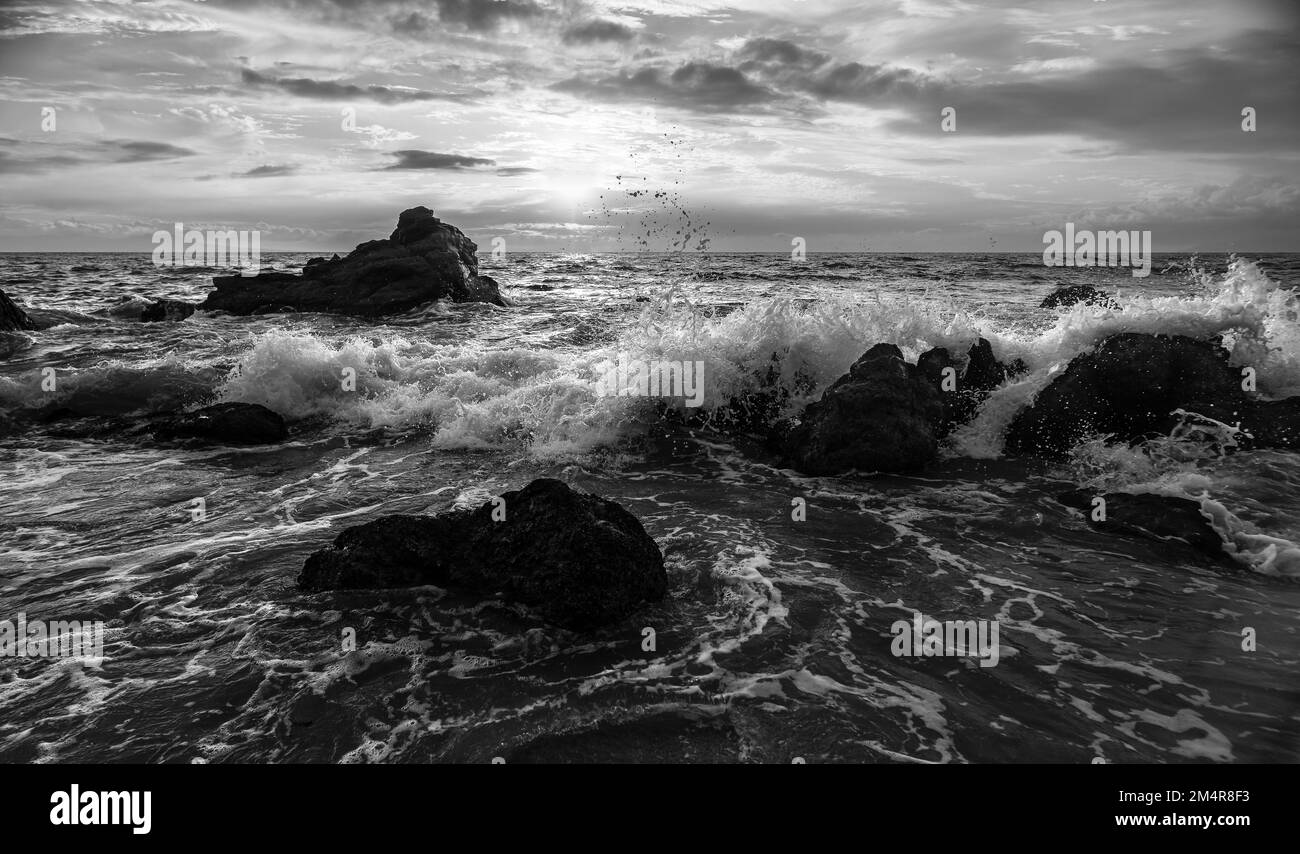Un'onda dell'oceano sta rompendo contro il cielo del tramonto in formato immagine ad alta risoluzione in bianco e nero drammatico Foto Stock