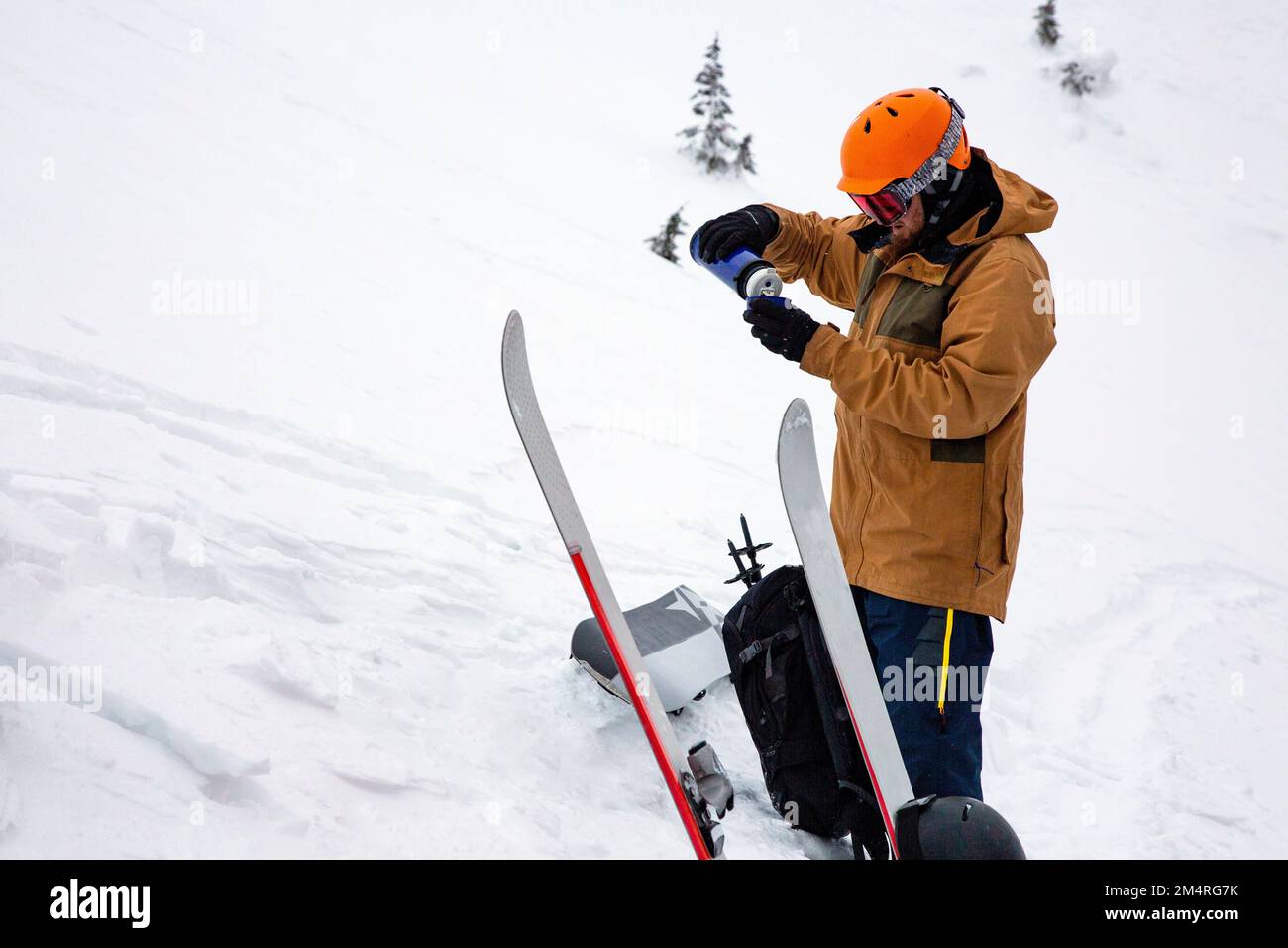 Un freerider versa il tè caldo da un thermos mentre sciate fuori in montagna. Concetto di freeride Foto Stock