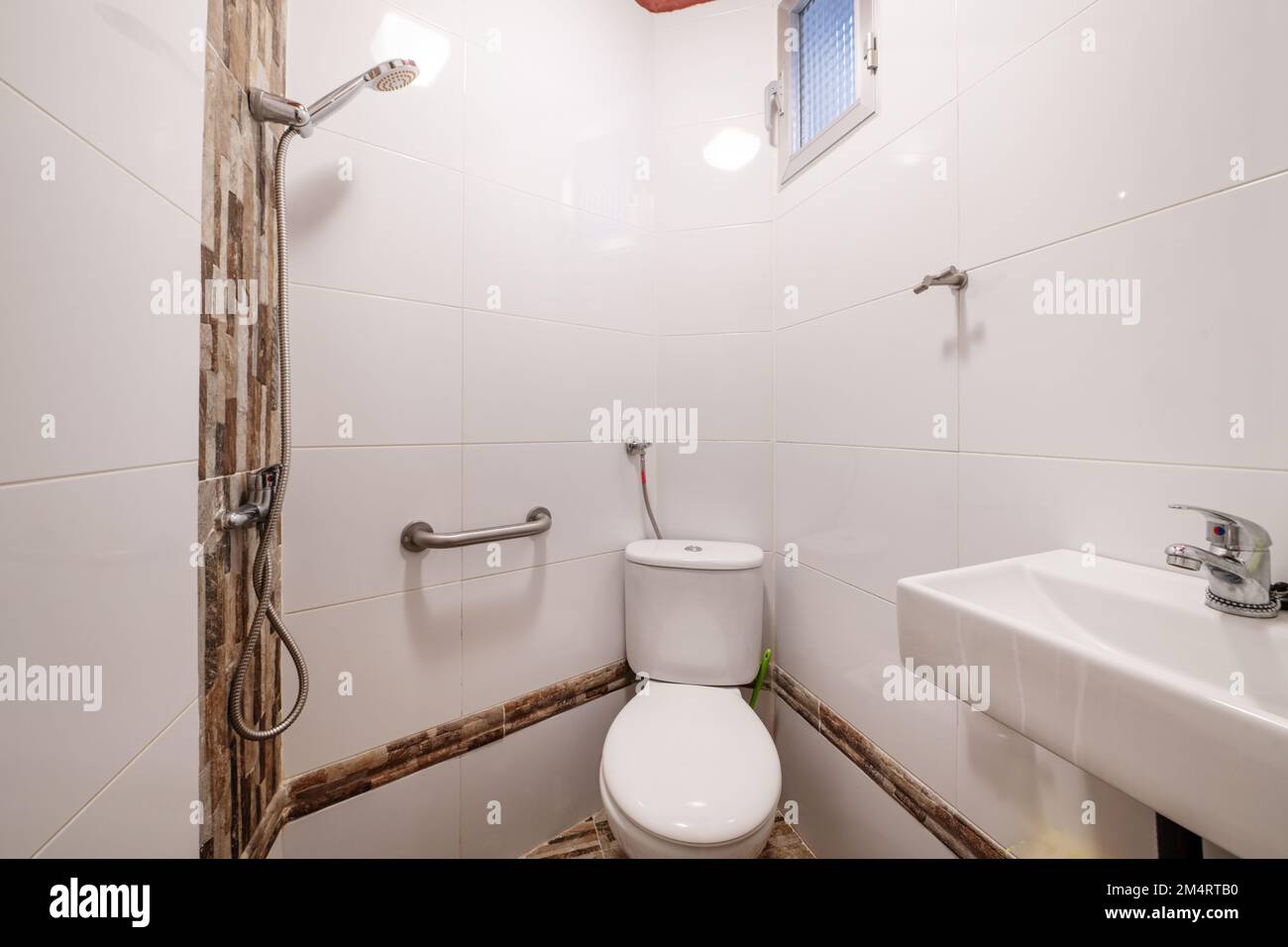 Piccolo bagno con lavabo in porcellana bianca sospesa, doccia senza schermi Foto Stock