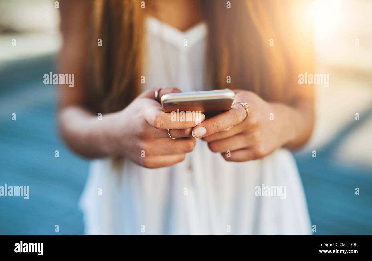L'unico modo per collegarsi in rete. una giovane donna irriconoscibile che invia un messaggio di testo mentre si è in piedi fuori. Foto Stock