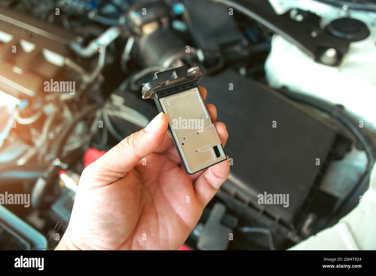 Il sensore di massa del flusso d'aria del sistema del collettore di aspirazione dell'aria del motore in mano meccanica automatica, concetto di parte automobilistica Foto Stock