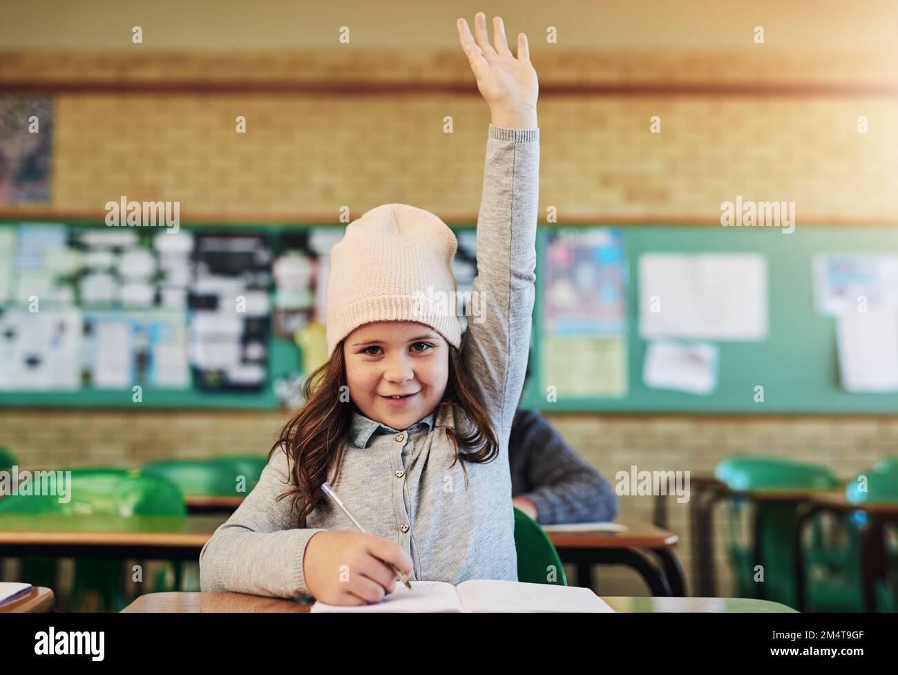 Il nostro piccolo genio della classe. Ritratto di una adorabile studentessa elementare che alza la mano in classe. Foto Stock