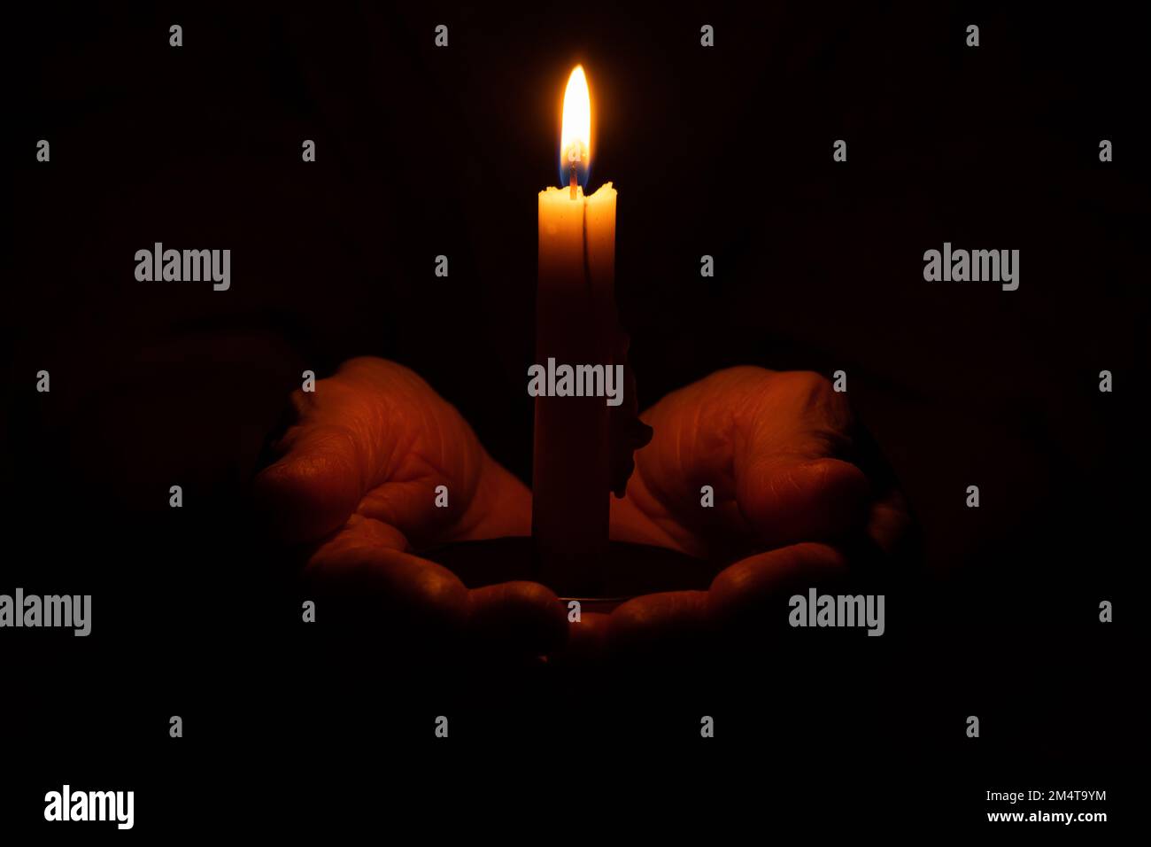 le mani della vecchia donna e la fiamma della candela al buio, la luce della candela, il lutto, la candela al buio Foto Stock