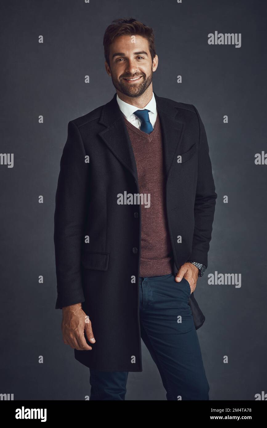 Affari con un lato di casual. Studio ritratto di un giovane uomo elegantemente vestito che si posa su uno sfondo grigio. Foto Stock