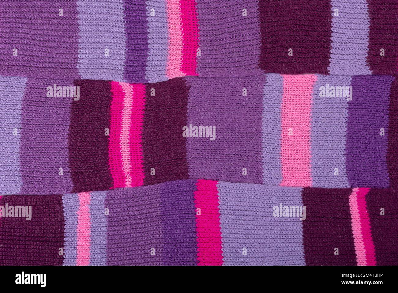Sfondo lilla lavorato a maglia. Grande tessuto lavorato a maglia con un motivo. Materiale delle pieghe ondulate. Foto Stock