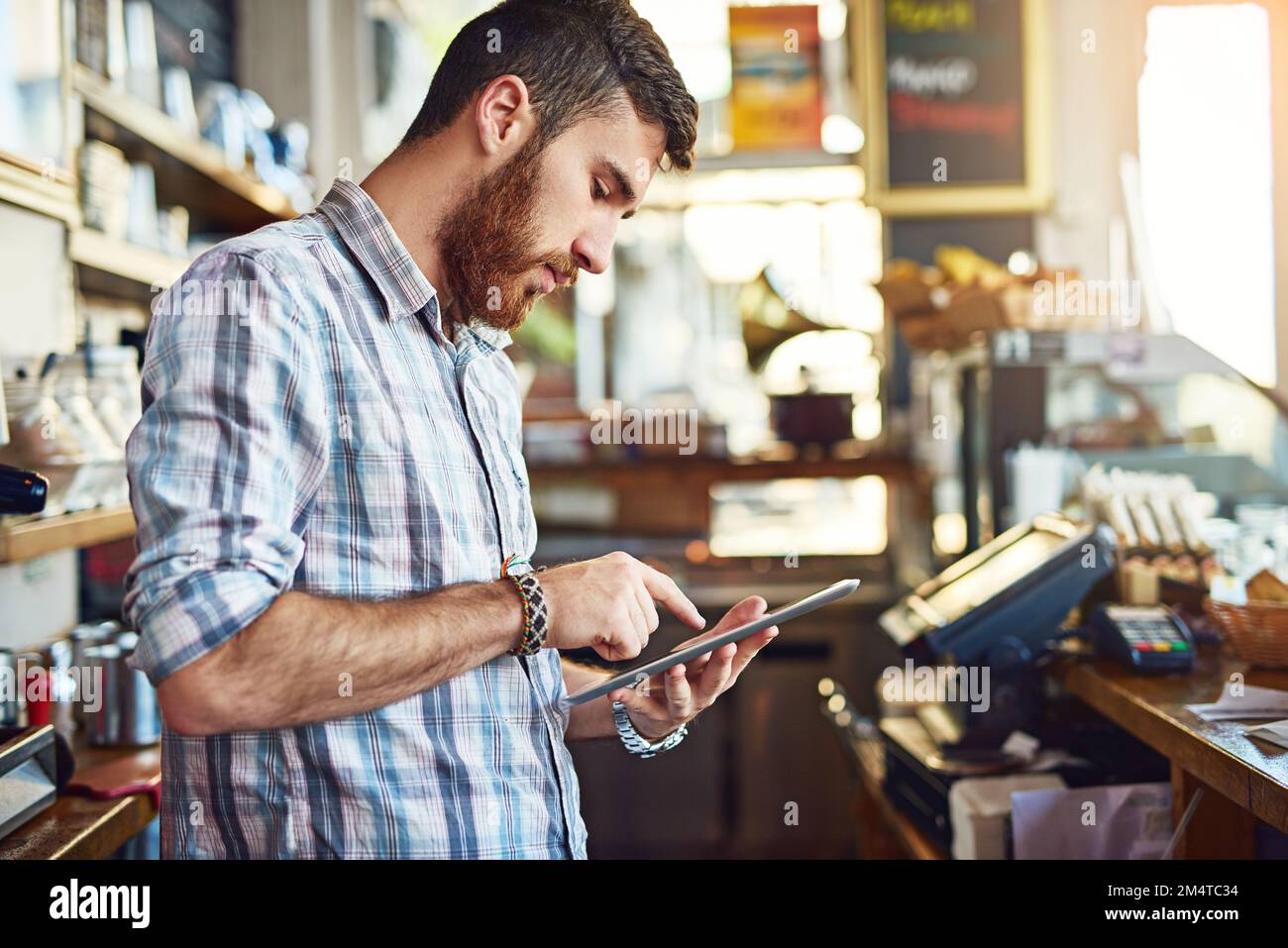 Mettere in funzione il suo nuovo business caffè. un giovane uomo che usa un tablet digitale mentre lavora in una caffetteria. Foto Stock