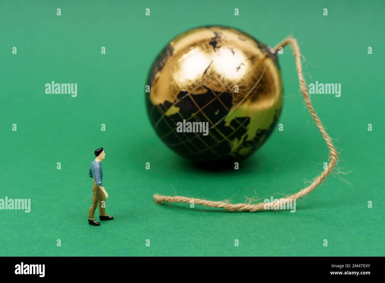 Concetto ecologico. Sulla superficie verde si trova un pianeta da cui emerge uno stoppino, vicino al quale si erge una figura umana. Foto Stock