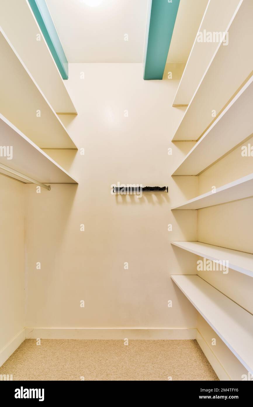 una passeggiata - in armadio con scaffali bianchi e mensole sulla parete, c'è una porta aperta Foto Stock